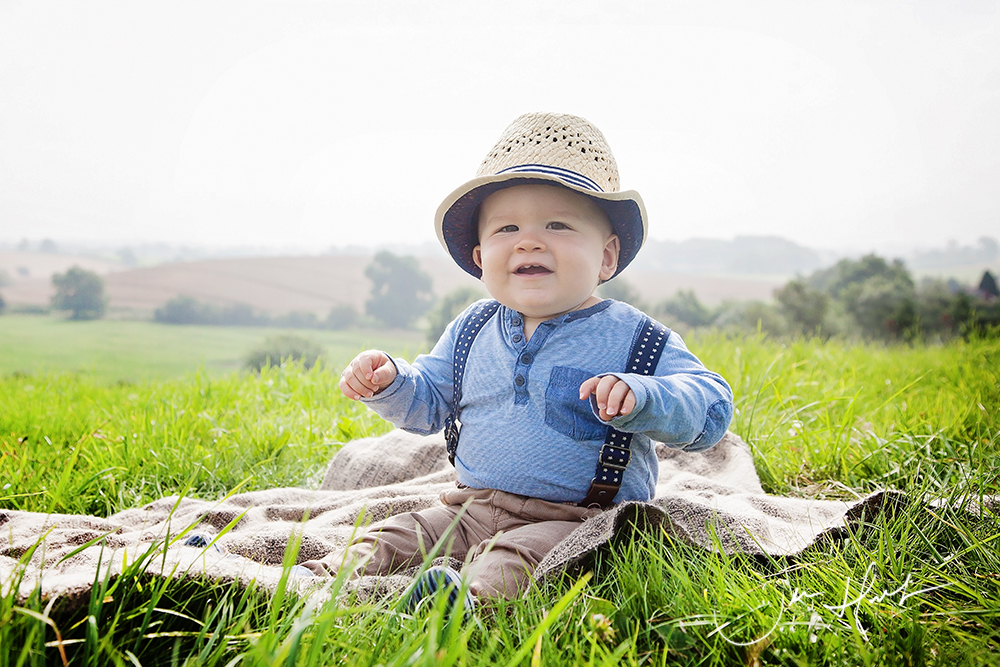 Spring baby and Family Outdoor photography. Little Boy Sitting on a rug wearing a sunhat. 